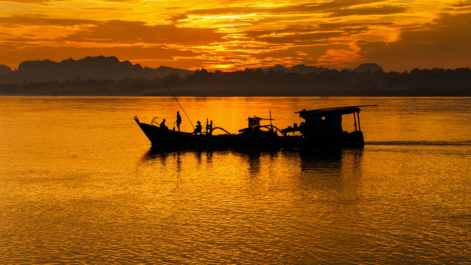 puesta de sol con barco a contraluz en un rio al sur de Myanmar